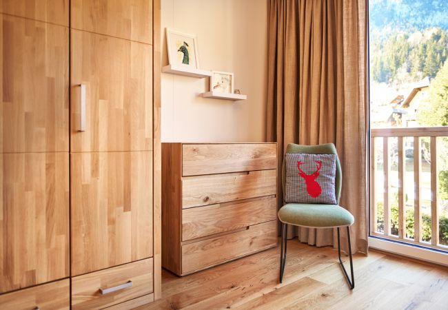 Schlafzimmer 1 mit Kleiderschrank und Sessel in der Ferienwohnung Alm Lodge A5 in Tauplitz